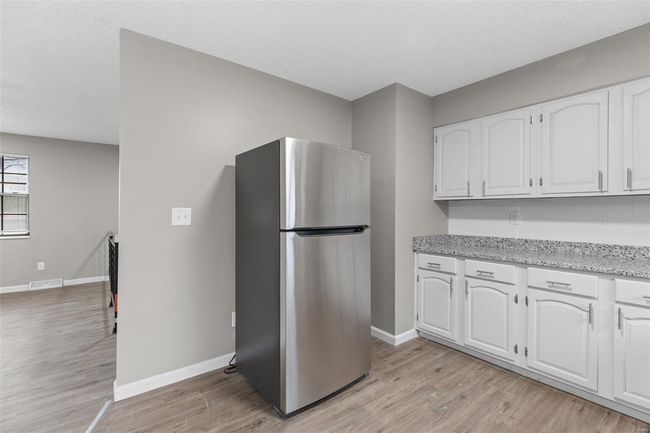 Kitchen with freestanding refrigerator, white cabinets, light wood-style floors, and visible vents | Image 12