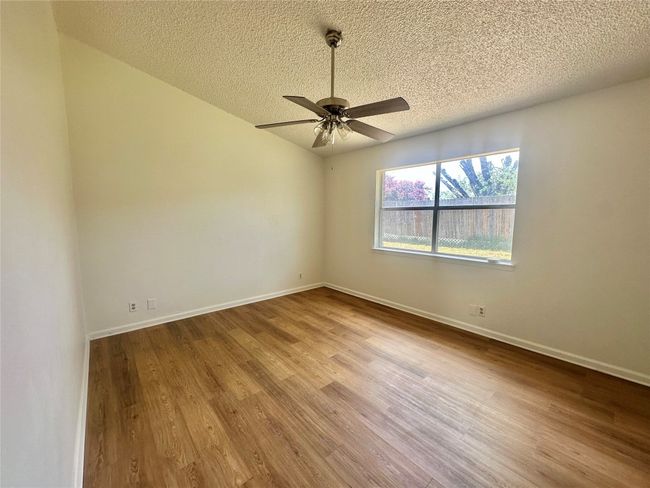 Spare room featuring a textured ceiling, wood finished floors, ceiling fan, and vaulted ceiling | Image 14