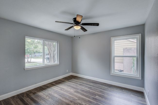 Empty room with dark wood finished floors, baseboards, and a ceiling fan | Image 6