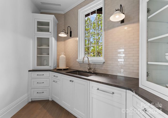 The scullery features custom cabinets, paneled dishwasher, and leathered quartzite. | Image 12