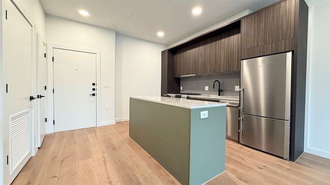 Kitchen with high end fridge, a center island, decorative backsplash, light wood-type flooring, and recessed lighting | Image 5