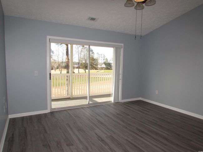 Living room with ceiling fan, dark LVP flooring and sliding glass door to your screen porch. | Image 30