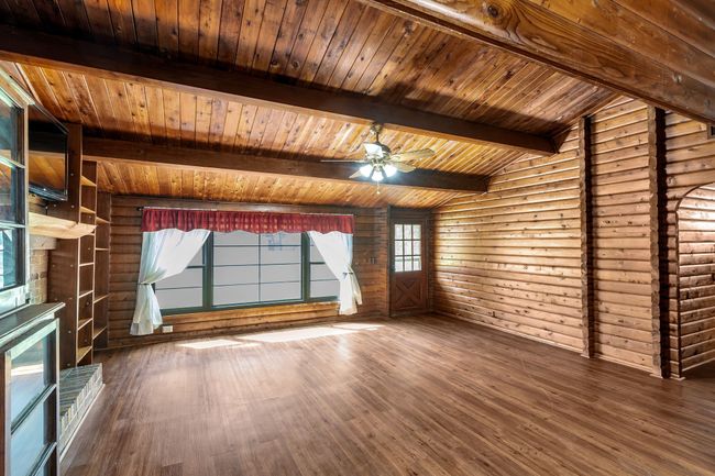 Living room featuring log walls, dark wood-style floors, wooden ceiling, and a ceiling fan | Image 7