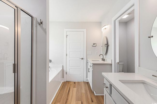 Bathroom featuring wood finished floors, a stall shower, a bath, and two vanities | Image 19
