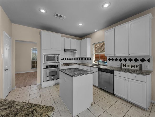 Kitchen featuring stainless steel appliances, light tile patterned floors, white cabinets, tasteful backsplash, and recessed lighting | Image 9