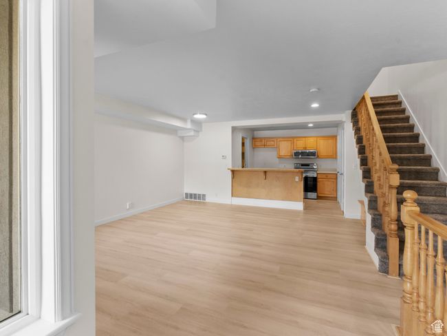 Unfurnished living room with light wood finished floors, recessed lighting, and stairway | Image 9