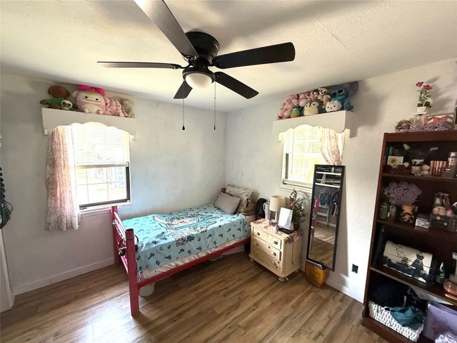 Bedroom with wood finished floors, a textured ceiling, multiple windows, and ceiling fan | Image 25