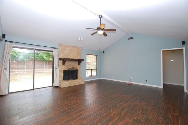 Unfurnished living room with ceiling fan, wood finished floors, and a fireplace | Image 4