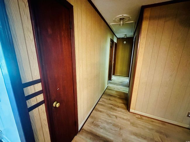 Hall with attic access, wooden walls, wood finished floors, and baseboards | Image 14