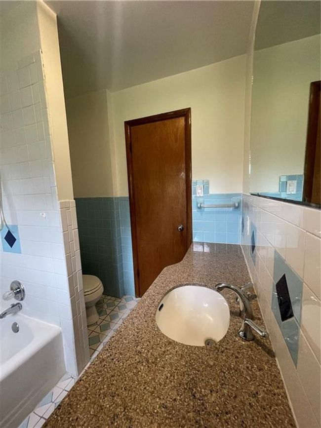 Full bath with tile patterned floors, tile walls, a wainscoted wall, toilet, and vanity | Image 22
