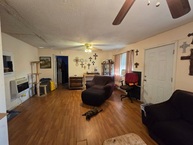 Living area with wood finished floors, heating unit, and a textured ceiling | Image 16