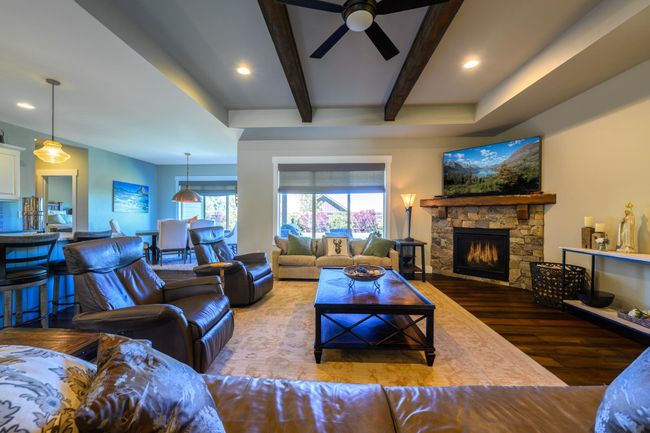 Living area featuring wood finished floors, a ceiling fan, a fireplace, beamed ceiling, and recessed lighting | Image 9