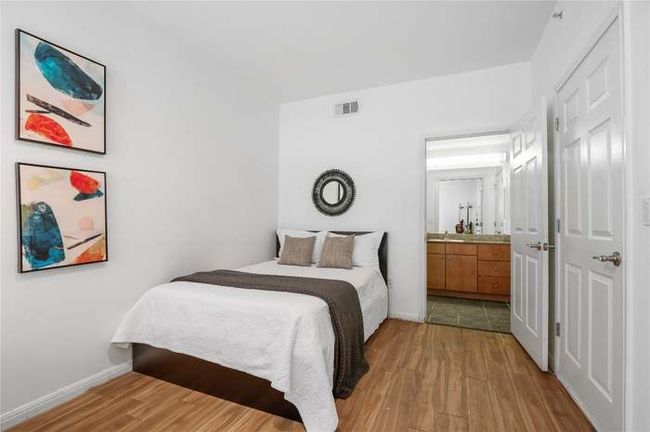 Bedroom featuring light wood finished floors, baseboards, and connected bathroom | Image 7