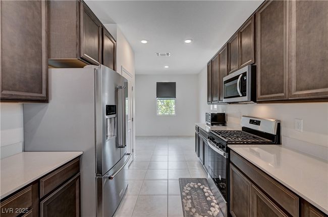Kitchen featuring stainless steel appliances, light countertops, dark brown cabinets, and recessed lighting | Image 13