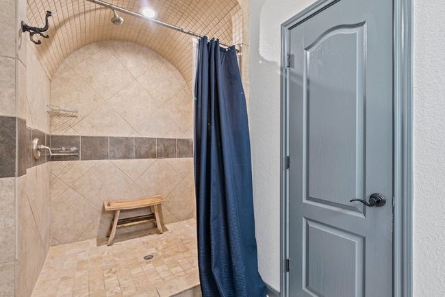 Bathroom featuring tiled shower and a textured wall | Image 17