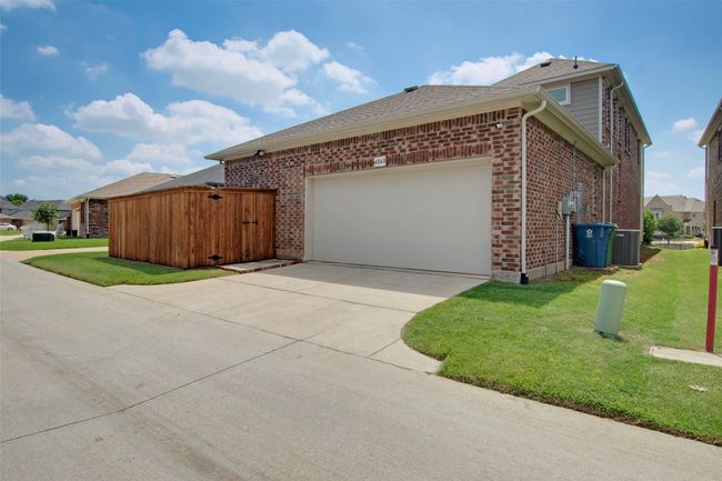 View of side of property with concrete driveway, a lawn, a garage, and brick siding | Image 30