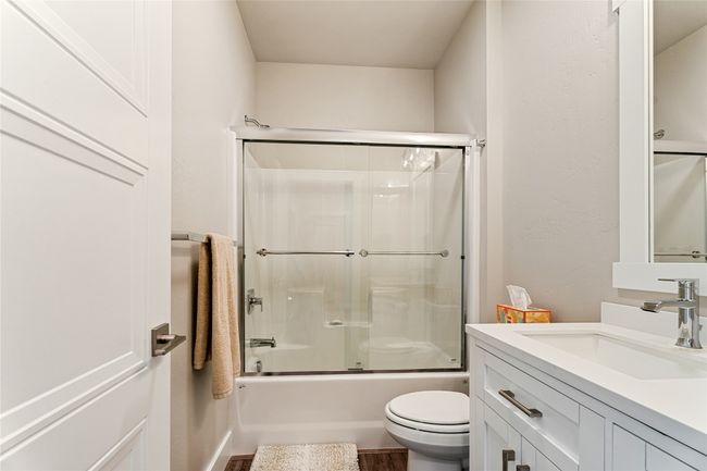 Full bath with vanity, toilet, combined bath / shower with glass door, and wood finished floors | Image 23