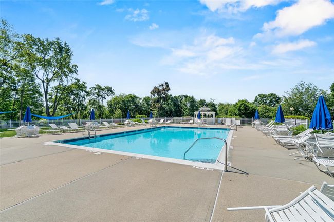 Community pool featuring a patio area and view of wooded area | Image 38