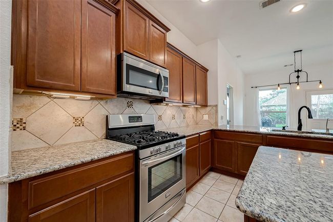 All granite countertops and tiled backsplash with Fridgedaire 6 burner gas stove | Image 12
