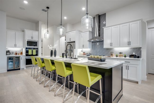 Kitchen with an enormous island, wine cooler, stainless steel appliances, and wall chimney range hood | Image 5