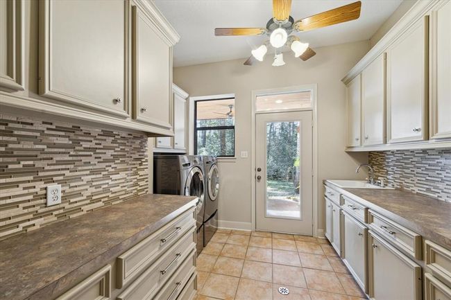 This well-appointed laundry room provides ample storage cabinets and drawers as well as a full-size porcelain sink which helps to make household management less of a chore. A hidden laundry shoot from the primary bath is also a plus! | Image 23