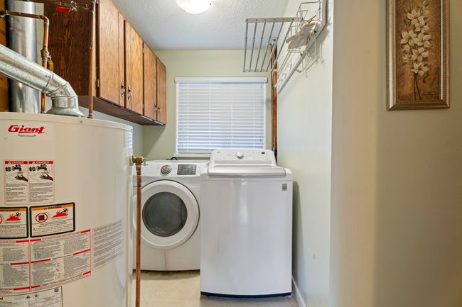 Clothes washing area featuring cabinet space, gas water heater, washer and dryer, and a textured ceiling | Image 14