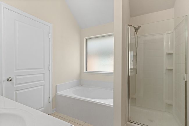 Full bath featuring a shower stall, a garden tub, tile patterned floors, lofted ceiling, and vanity | Image 19