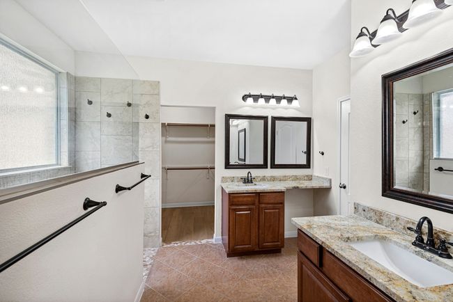 Bathroom featuring a walk in shower, two vanities, tile patterned floors, and a walk in closet | Image 30
