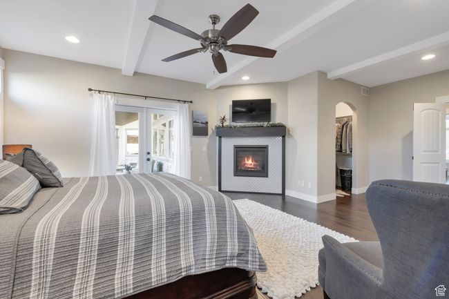 Bedroom with baseboards, french doors, beam ceiling, arched walkways, and wood finished floors | Image 23