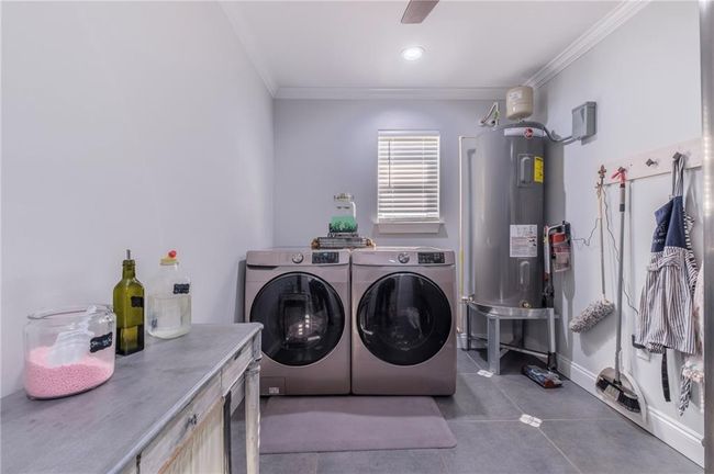 Washroom featuring washing machine and clothes dryer, water heater, and crown molding | Image 23