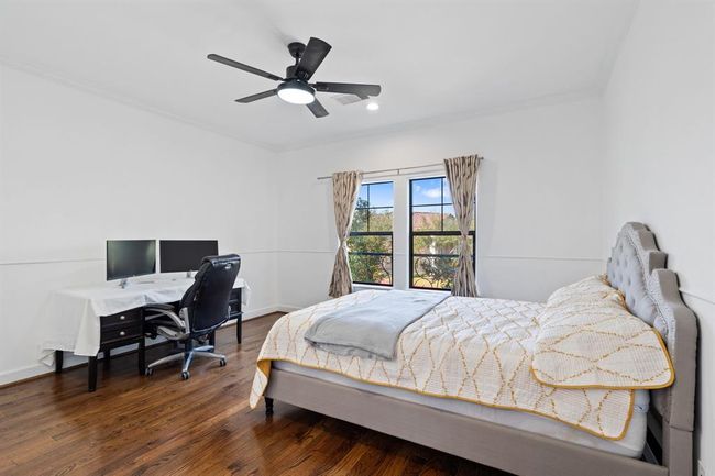 Spacious secondary bedroom on the second floor featuring oversized windows that fill the room with natural light, hardwood flooring, and a ceiling fan for added comfort. This bright and inviting space is perfect for rest and relaxation. | Image 45