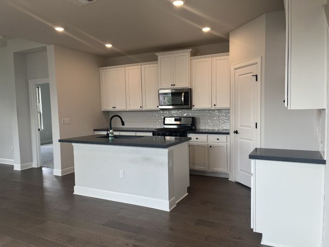 Kitchen with white cabinetry, dark countertops, appliances with stainless steel finishes, and a sink | Image 5