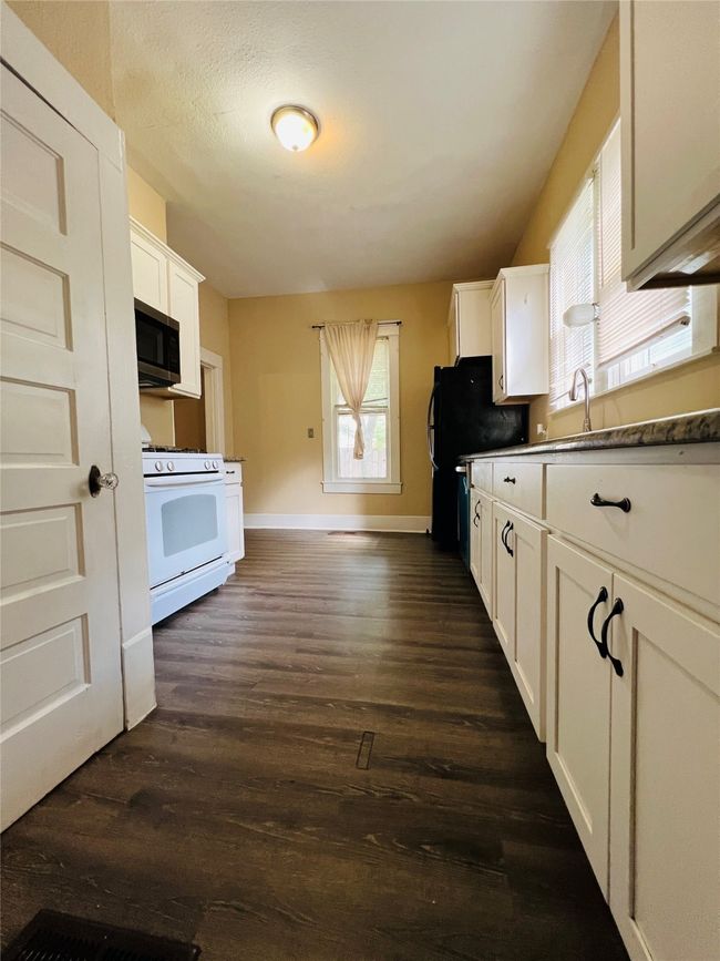 Kitchen with gas range gas stove, stainless steel microwave, white cabinetry, and dark wood-type flooring | Image 17