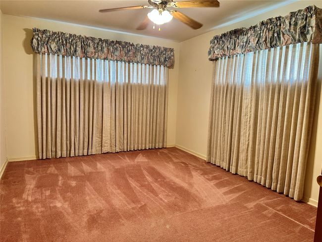 Empty room with carpet flooring, baseboards, and ceiling fan | Image 9