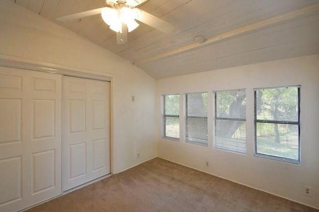 Unfurnished bedroom featuring vaulted ceiling, multiple windows, carpet flooring, a closet, and ceiling fan | Image 9