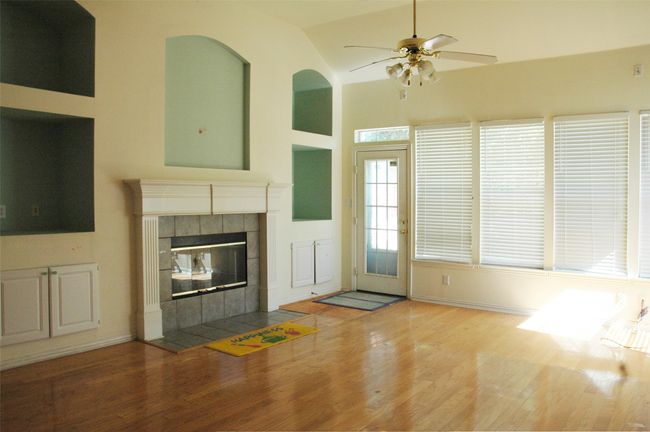 Unfurnished living room with wood finished floors, ceiling fan, a tiled fireplace, and lofted ceiling | Image 4