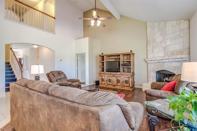 Living area featuring a fireplace, arched walkways, high vaulted ceiling, a ceiling fan, and stairway. | Image 17