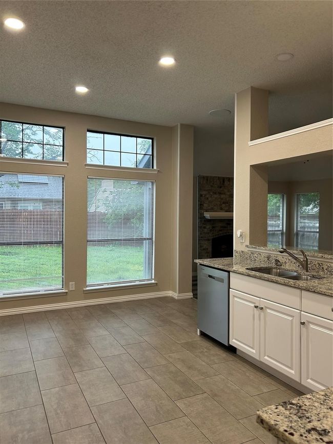 Kitchen featuring stainless steel dishwasher, recessed lighting, white cabinetry, light tile patterned floors, and light stone counters | Image 8