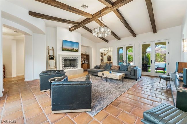 Vaulted ceilings with new wood beams, fireplace, new light fixture, and double french doors to backyard covered patio. | Image 4