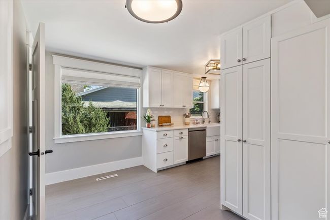 Kitchen with stainless steel dishwasher, healthy amount of natural light, white cabinetry, and light countertops | Image 17