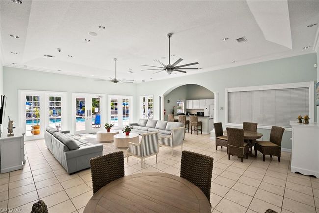 Living area with a tray ceiling, french doors, light tile patterned floors, arched walkways, and ceiling fan | Image 37