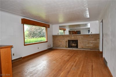 Unfurnished living room featuring a stone fireplace and wood-type flooring | Image 3