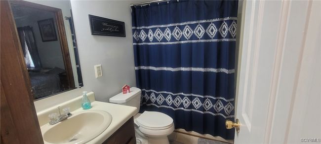 Bathroom with a shower with shower curtain, toilet, and vanity | Image 5
