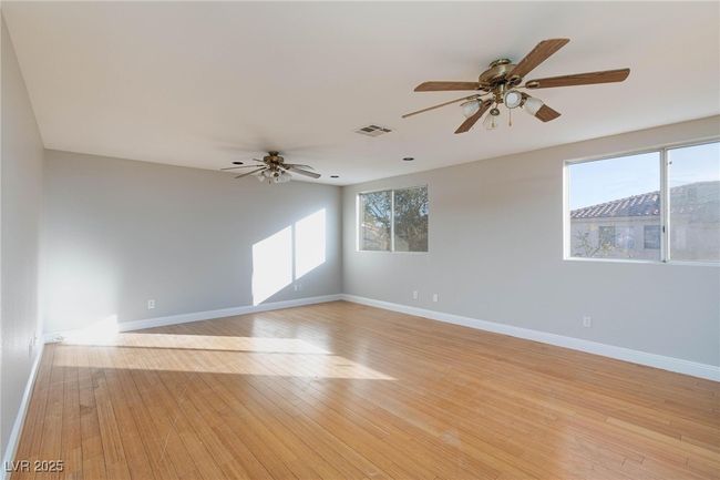 Unfurnished room with a wealth of natural light, visible vents, light wood-style flooring, and ceiling fan | Image 19