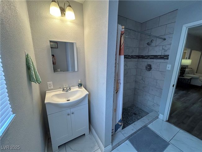 Full bath with vanity, tiled shower, and a textured wall | Image 21