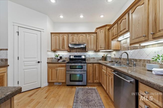 Kitchen with appliances with stainless steel finishes, light wood-type flooring, decorative backsplash, recessed lighting, and under cabinet range hood | Image 21
