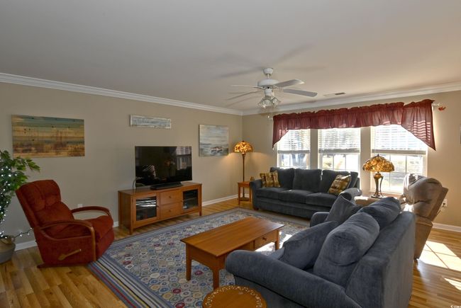 Living room with ceiling fan, crown molding, and light hardwood / wood-style flooring | Image 9