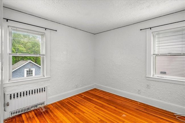 Unfurnished room featuring radiator heating unit, a textured ceiling, and hardwood / wood-style flooring | Image 13
