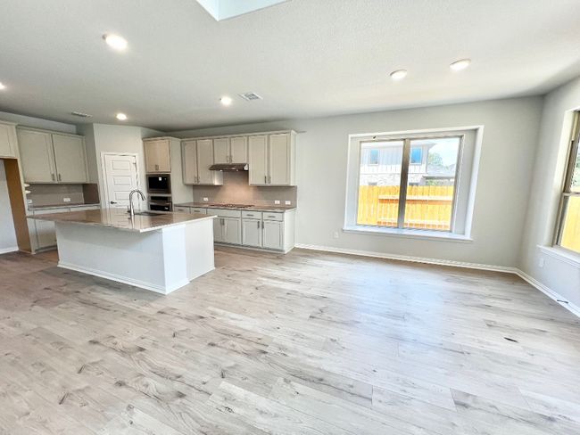 Kitchen with decorative backsplash, a kitchen island with sink, a skylight, recessed lighting, and light wood-style flooring | Image 9