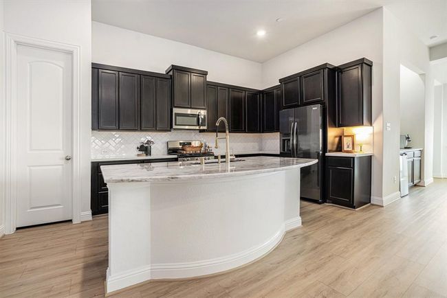 The kitchen has beautiful finishes including gorgeous quartzite countertops, a granite sink, stainless appliances, and gold faucets | Image 7